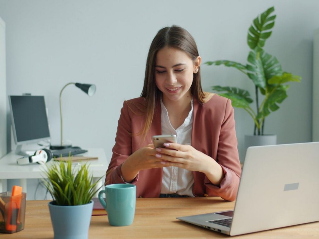 A professional reviewing a message on her phone at an office desk